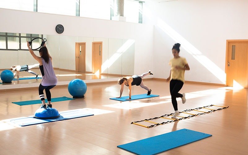 Clase de entrenamiento por estaciones en la sala, con fitballs, escalera de agilidad y esterillas